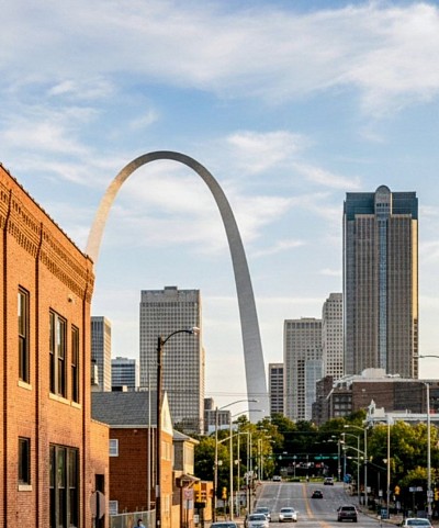 A downtown St. Louiscity street with hotels, commercial properties and the St. Louis arch in the background